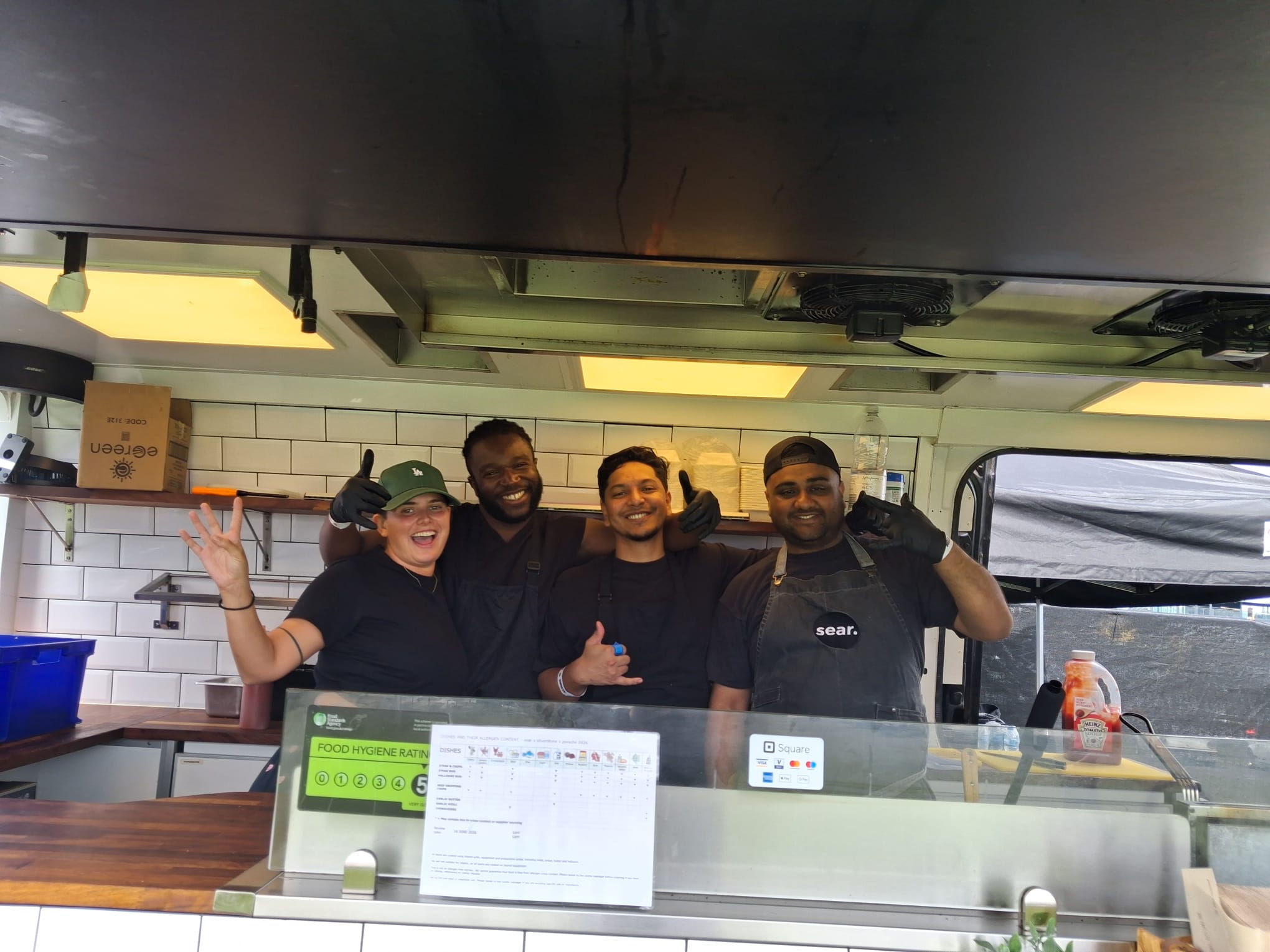 Four sear team members smiling together inside their food truck